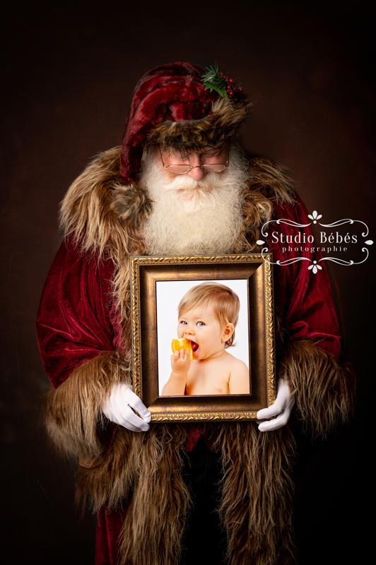 Un magnifique Père Noël aux gants blans porte le portrait d'un jeune enfant encadré